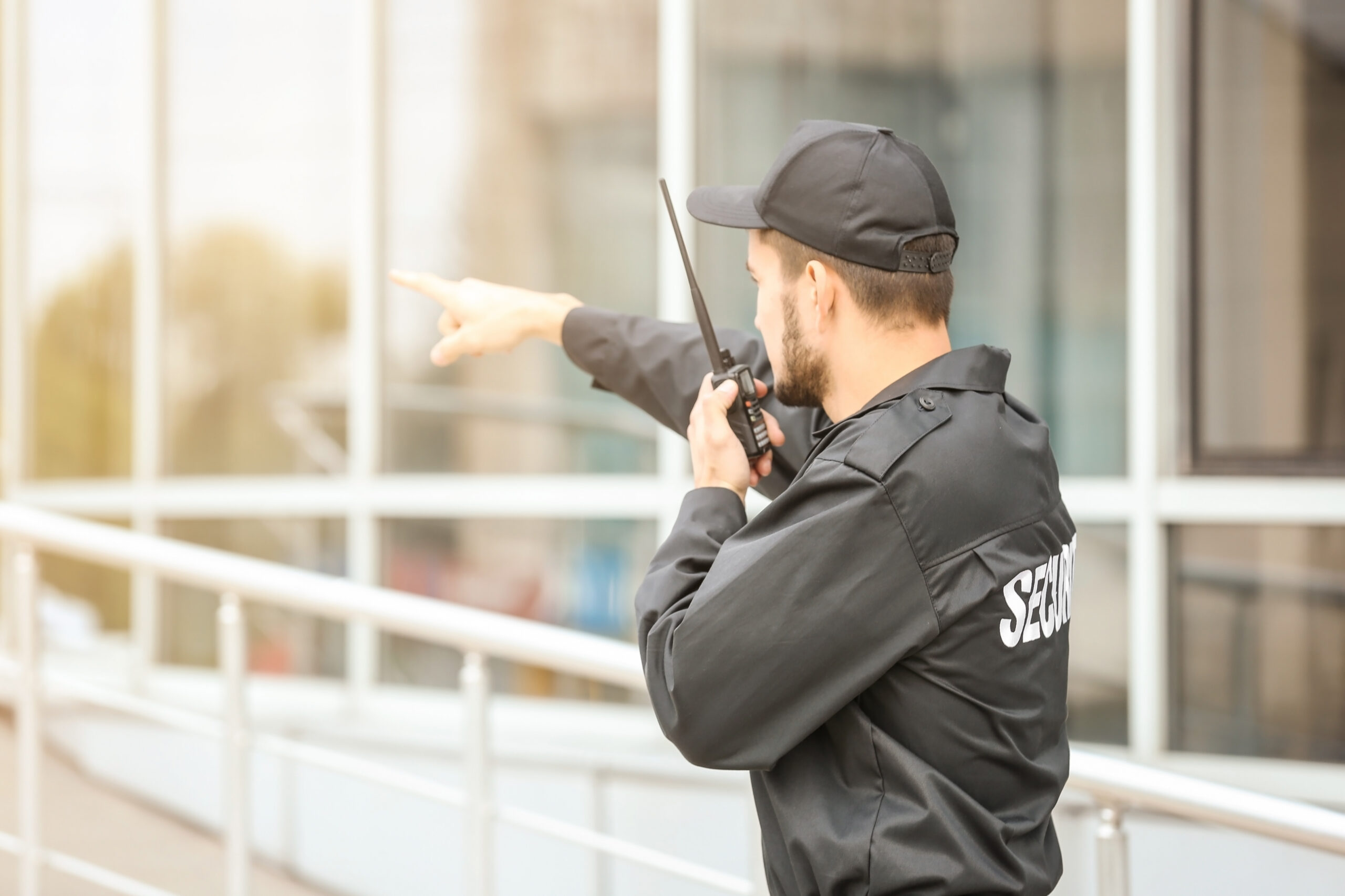 Male,Security,Guard,Using,Portable,Radio,Transmitter,Near,Building,Outdoors